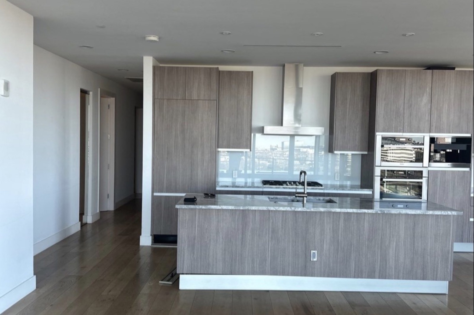 A modern kitchen in grey oak with stone counters and integrated appliances — design-build remodeling for Wellesley, Massachusetts homes